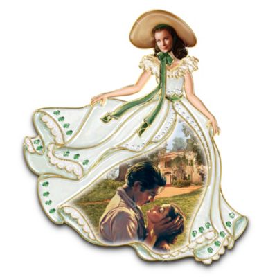 As willful as she was beautiful, Scarlett O'Hara blazed her way through the all-time classic film Gone With the Wind and the world has loved her ever since. Now this striking wall decor showcases Scarlett wearing one of her most memorable costumes, with her flowing skirt revealing a full-color montage of scenes from the film.Be forever reminded of Scarlett's passions and fashions with this limited-edition Scarlett O'Hara memorabilia wall decor, available only from The Bradford Exchange. Scarlett wears the unforgettable ensemble of the Twelve Oaks barbecue. Handcrafted in fine porcelain, the plaque's low-relief detailing is adorned with sparkling, emerald-green simulated jewels (to match Scarlett's eyes!), opalescent glazes and lavish 22K-gold accents. But Scarlett O'Hara waits for no one, so don't miss out. Be sure to order now!