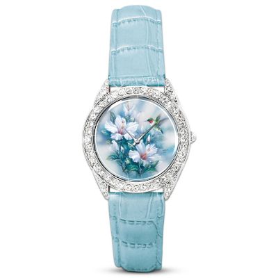 Invoking the tranquility of nature and nature's crown jewels, the hummingbird takes flight in this stunning Lena Liu artistic watch designed by award-winning artist Lena Liu to showcase one of her original paintings. The watch face of this handcrafted timepiece radiates with the color and romantic grace of a hummingbird garden and is surrounded by a sparkling bezel of Swarovski crystals in a pave setting. Another glittering Swarovski crystal adorns the crown.This Lena Liu wearable art is a fine jewelry exclusive from The Bradford Exchange with accurate quartz movement. The leather straps adjust to fit most wrists and beautifully coordinate with the color of the art. The custom-designed case makes the perfect finishing touch. Lena Liu art is highly sought; strong demand is expected. Order now!California Residents click here for Proposition 65 notice.