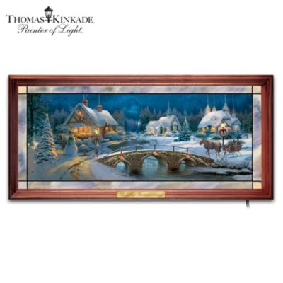 No artist captures the warm glow of the holidays quite like The Painter of Light. His signature style always dazzles. Now you can get two holiday-themed works of art in one with this first-of-a-kind Thomas Kinkade stained-glass panorama, available exclusively from The Bradford Exchange. This exquisite Thomas Kinkade illuminated wall decor is handcrafted in stained glass and features two magnificent images in one. At the flip of a switch, a radiant winter day filled with a horse-driven carriage crossing a cobblestone bridge transforms into a starlit nighttime holiday scene with the effect of lighted homes, trees and street lamps. Plus, this illuminated holiday wall decor includes a walnut-finished wood frame with golden name plaque. High demand is expected and you won't want to miss out. Order now!