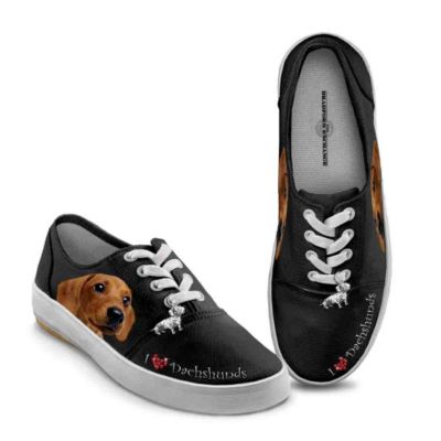 Do you have a case of puppy love? Anyone who's ever adored a Dachshund will be kicking up their heels at the beauty, style and heart-stealing art featured on these charming Dachshund shoes, a fine apparel design available only from The Bradford Exchange. One look into the soulful brown eyes of the delightful pup that graces these Dachshund sneakers, and you'll want to wear them wherever you go, just to keep in step with your best little buddy.  Custom-crafted in stylish black canvas, these exclusive Dachshund shoes for women are reinforced with rubber outsoles, have a cotton-terry lining for superior durability, and foam-cushioned footbeds for extra comfort. In addition to the full-color Dachshund portrait that graces each shoe side, the sweet sentiment "I &hearts; Dachshunds" is crafted with a red faux-jeweled heart; plus, a silvery sculptural Dachshund charm dangles from the laces of each shoe. For perfectly fetching fashion, these Dachshund sneakers are definitely something to bark about. Order now!