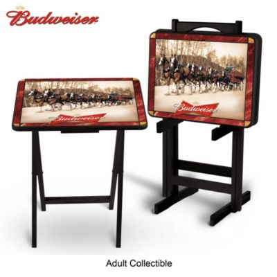 In a first-of-its-kind design, the famed Budweiser&reg; Clydesdales step lively on a set of two handsome tray tables for a refreshing way to serve up some good times at any occasion! Join the celebration of the Great American Beer with this striking Budweiser decor in a tray table set, available exclusively from The Bradford Exchange.This set of two wooden tray tables features imagery of the official Clydesdales imagery from the Budweiser archives, classic bow-tie logo, marbleized decorative border and a rich black finish that is both water- and heat-resistant for long-lasting quality. Plus, this keepsake includes a FREE storage stand with a space-saving design to safely hold your tray tables and complements any decor, or you can create a Budweiser lounge or a Budweiser bar. Strong demand is expected. Order now!