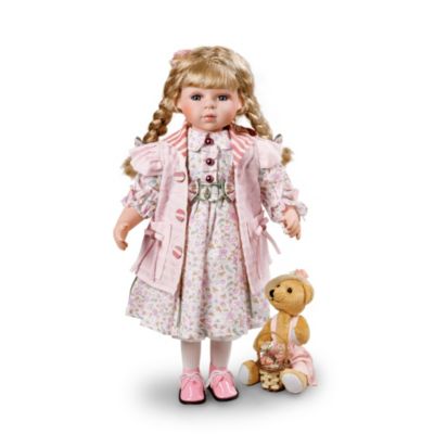 It's perfectly clear that pink is the color Therese likes best, and with her blonde hair and rosy cheeks, she looks so good in it! In fact, this little lady likes it so well that she has even dressed her favorite little bear companion all in pink, to match her own outfit! Therese is a vintage style porcelain doll in an intricate layered costume that shows off many different shades of pink. It features an eye-catching mix of floral patterns, stripes and soft pastels, with fancy button accents. Her little plush bear looks quite pleased to be wearing pink, and holds a little basket of fabric flowers in that same shade.Therese is ready to charm you with her vintage-style details, available exclusively from The Ashton-Drake Galleries. Her fine, hand-painted porcelain features are a delight, and she has hand-set eyes, realistic eyelashes and silky blonde hair fashioned into long braids. This genuine collectible porcelain doll would give anyone a rosy outlook, so be sure to order now!