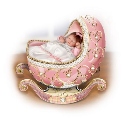 Peter Carl Faberge's jeweled masterpieces are famous for their opulent detail. Now, you can treasure a first-ever collectible Faberge-style musical cradle featuring a lifelike miniature baby doll that is sure to become your own family heirloom. Remove the baby doll from her cradle to examine her soft hair, fabric baby clothes, and tiny, hand-painted head and hands.Your heart will melt at the sight of this lifelike miniature baby doll and ornate musical cradle, available exclusively from The Ashton-Drake Galleries. The luxurious porcelain cradle is hand-set with Swarovski&reg; crystals, simulated pearls and hand-painted 22K-gold accents. Plays the comforting melody of "Brahm's Lullaby." But don't delay - strong demand is expected, and you don't want to miss out. Order now! California Residents click here for Proposition 65 notice.