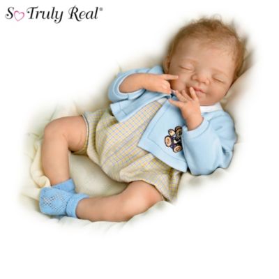 Shhh! These adorable sleeping angels need their rest! Their sweet, smiling faces are so content and precious, you'll want to watch them slumber for hours. This lifelike baby doll collection of twins by renowned Master Doll Artist Brigit Gutzwiller is crafted of RealTouch&reg; vinyl that feels soft to the touch, and skillful sculpting and hand-painting capture the sweet and expressive features. Arriving first is Issue One, Smiling Sweetly, Benjamin, and his sister joins her soon after as Issue Two, Gentle Dreams, Lauren. Each issue arrives separately.These collector newborn baby dolls are So Truly Real&reg; dolls exclusively from The Ashton-Drake Galleries, and they fit perfectly in your arm when you pick them up. Take a look and you'll fall in love with these adorable twins that feature wisps of baby-fine hair, delicate eyelashes, perfectly shaped fingers and toes, and realistic folds on their little legs and knuckles. Sized at 18" long, similar to real newborns, their eyelids have a thin, translucence appearance. These lifelike vinyl baby dolls are even lightly scented to give the impression of newly powdered skin. This terrific twosome wears hand-tailored, coordinating blue and yellow embroidered outfits. Strong demand is expected, so order now!
