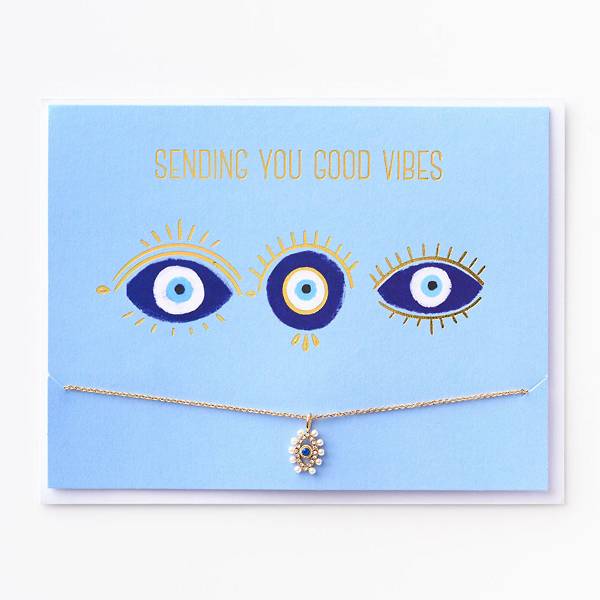 Greeting card features cool eyeball designs with gold foil details and lettering that reads, Sending you good vibes. Includes a delicate gold bracelet with a beautiful evil-eye charm.