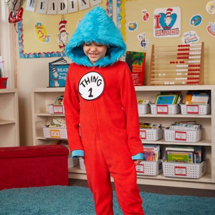    A happy child wearing a Thing 1 costume in a Seuss-themed reading corner