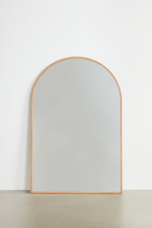 A large, gold arched mirror leaning against the wall on the floor